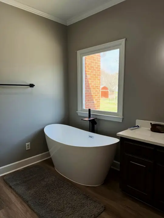 Bathroom with a freestanding tub under the window and a dark vanity