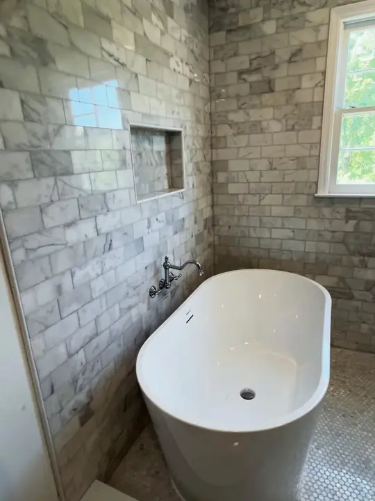 Wet room with grey subway tile, a niche and a freestanding tub