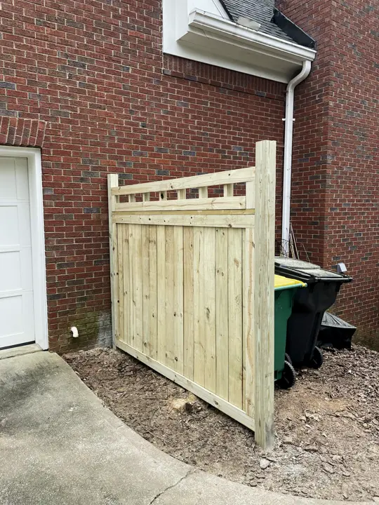 New privacy fence panel and gate beside a brick house