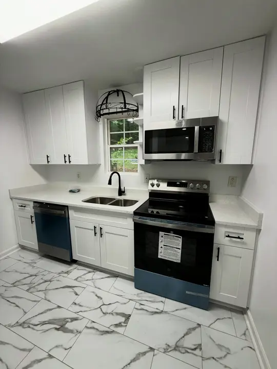 The same kitchen after: white shaker cabinets, new counters and stainless appliances