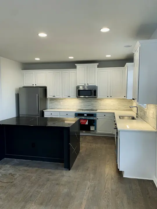 White shaker kitchen with a black island and LVP floor